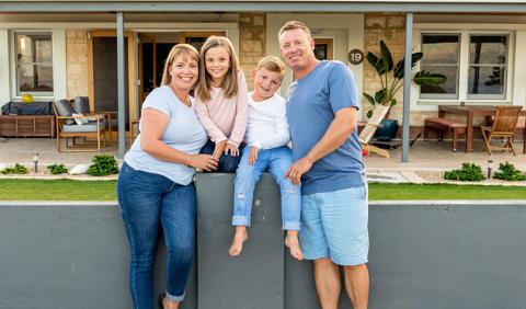 Family posing for picture outside their home.